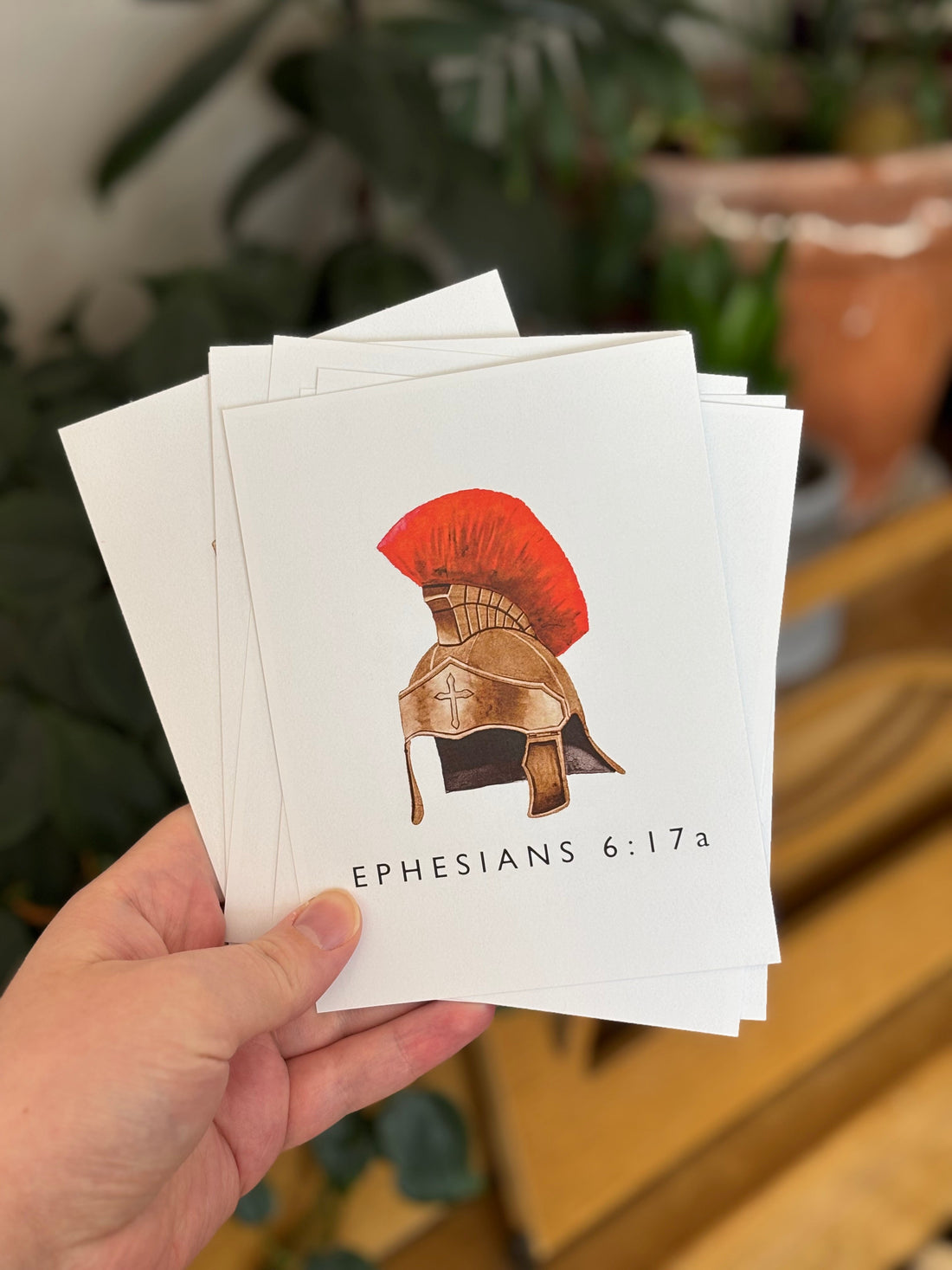 Hand holding Bible memory flashcards with Ephesians 6:17 and a plumed helmet on the front