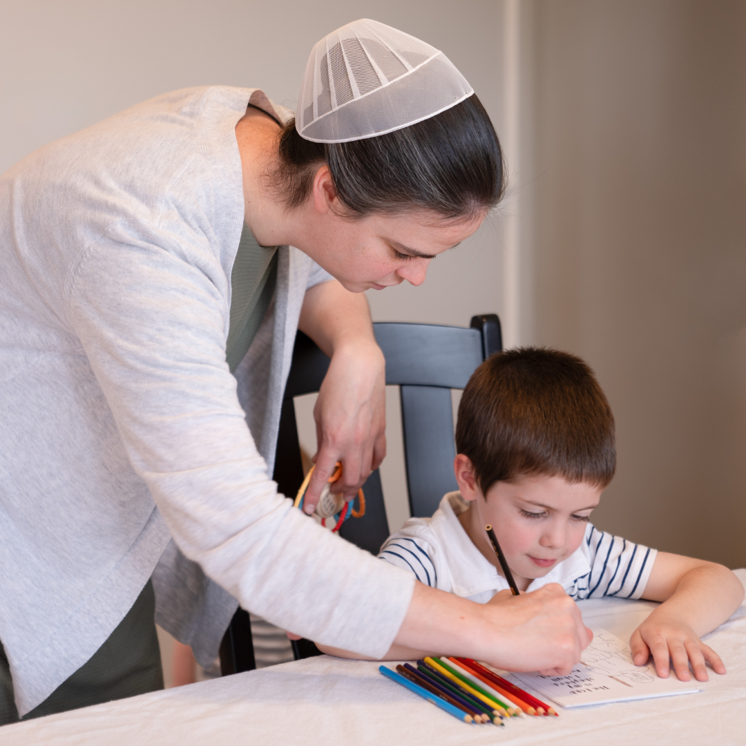 A Mennonite lady helping a boy color Psalm 23 coloring page at a table